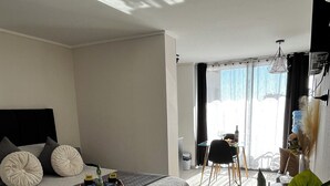 Un dormitorio moderno con una cama grande, una mesita con una botella y un vaso, y una silla.