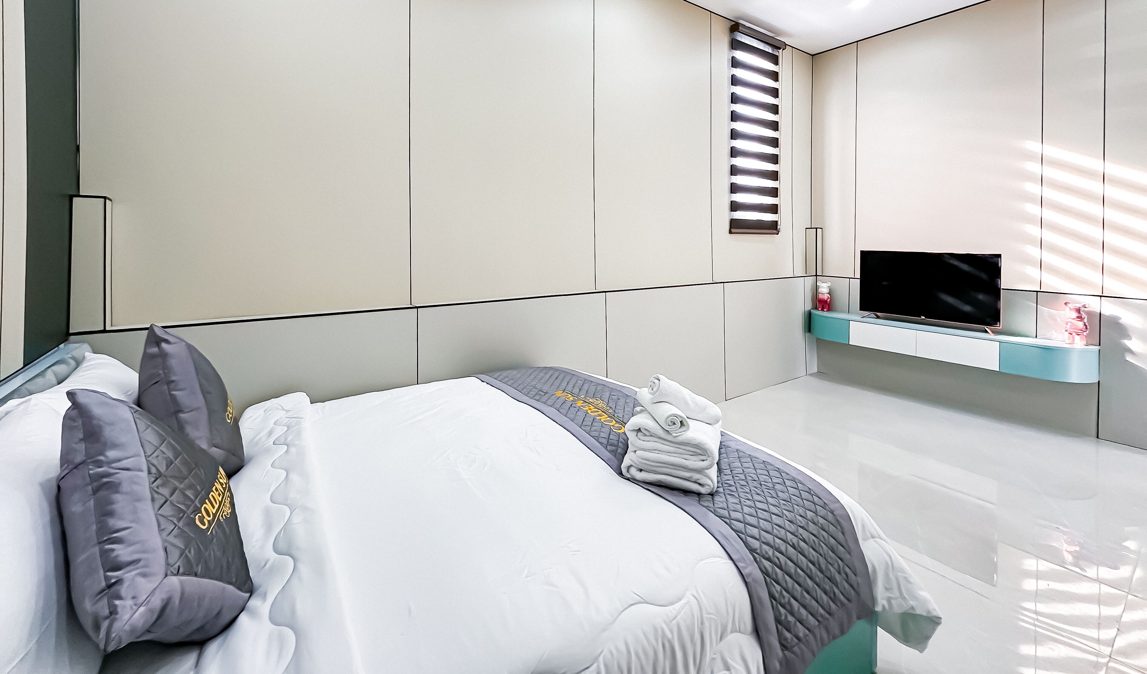 Un dormitorio moderno con cama, televisor y armarios empotrados.
