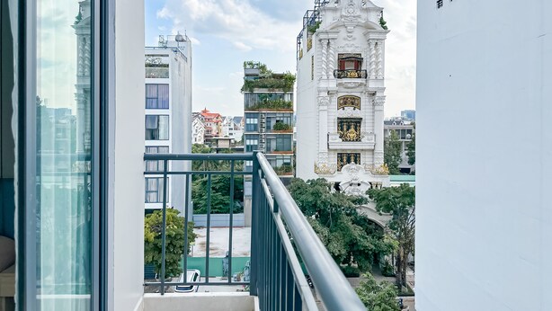 A balcony with a view of modern buildings, including a white ornate structure with gold accents. - Golden Sun Hotel Apartments 5 (Ho Chi Minh City)