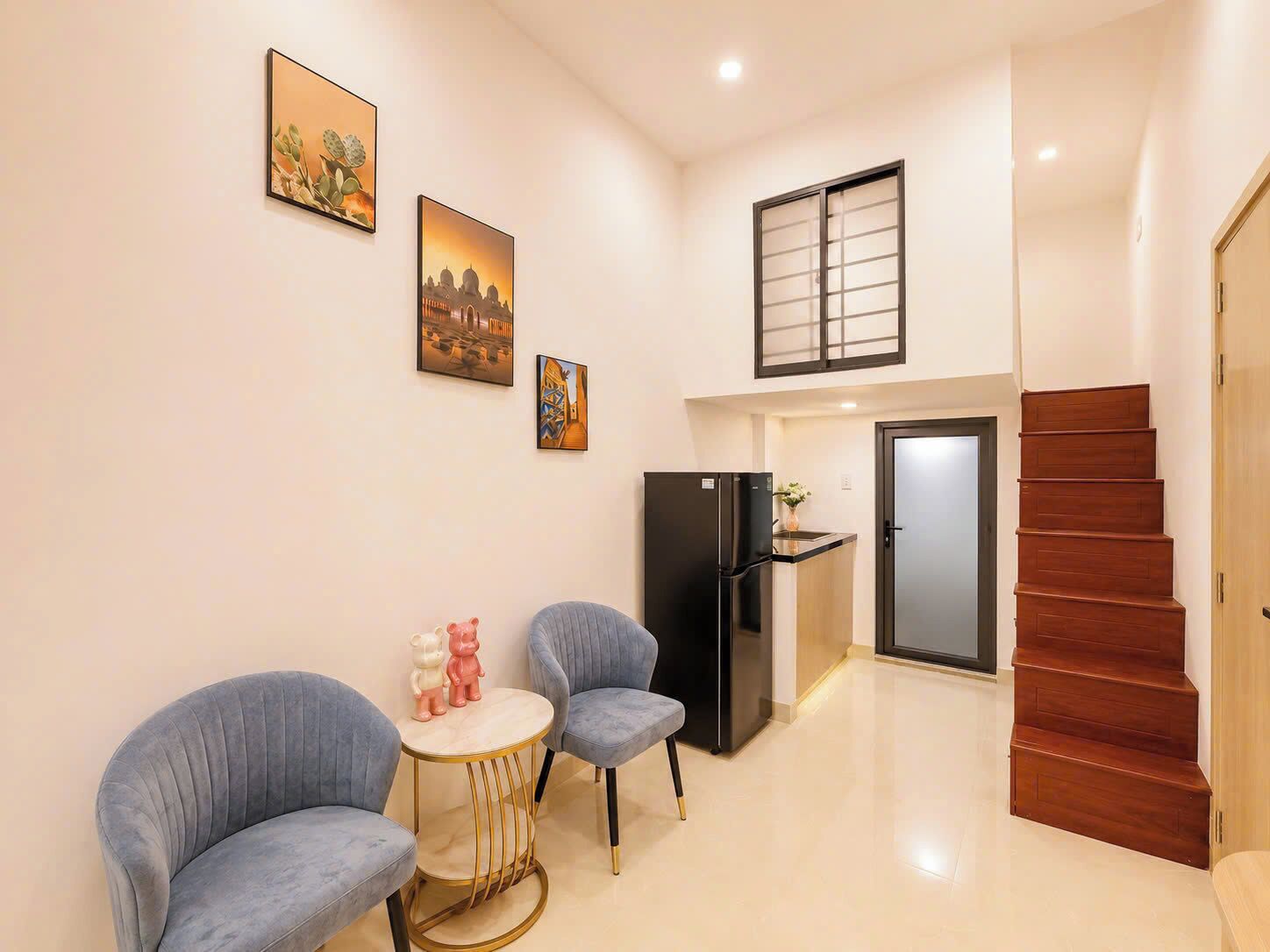 A modern living space with a dining area, a kitchen, and a staircase.