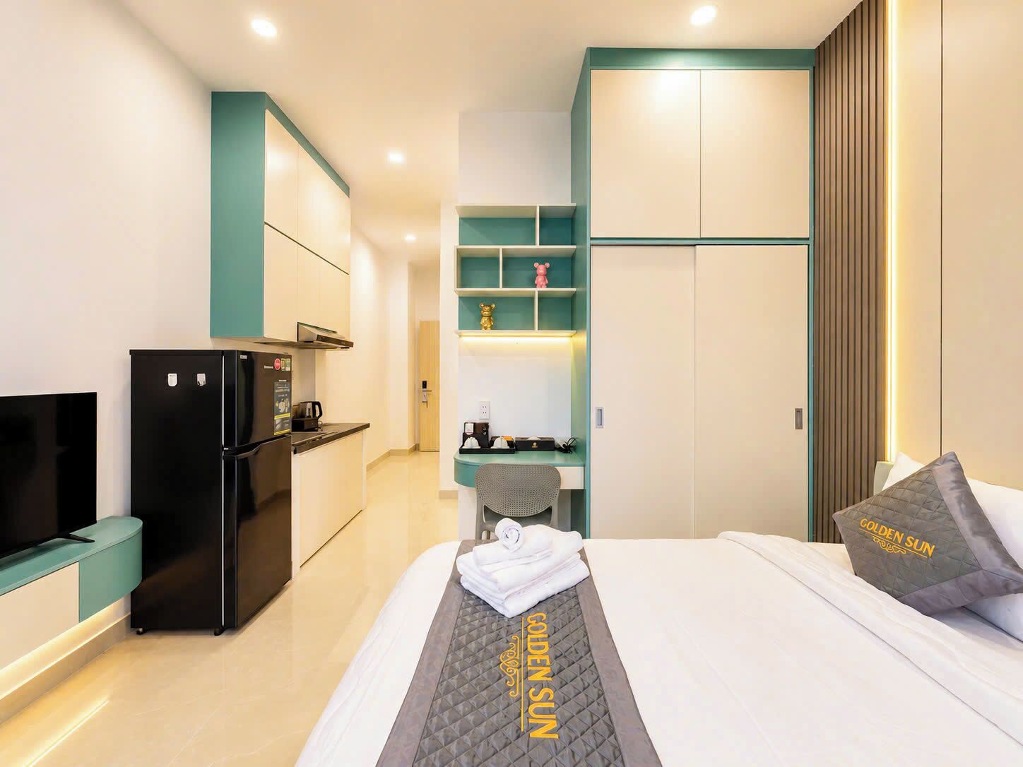 A hotel room with a bed, a desk, a refrigerator, and a television.