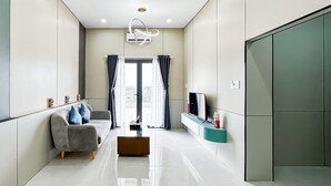 A modern living room with a sofa, a coffee table, and a TV on a stand. - Golden Sun Hotel Apartments 5 (Ho Chi Minh City)