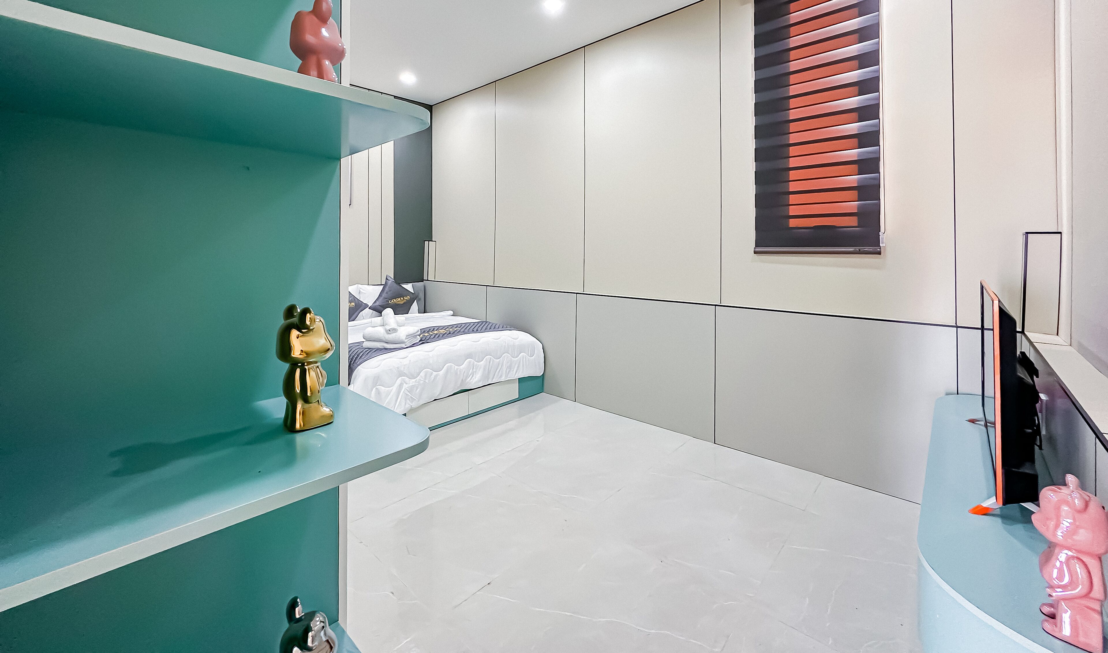 A modern bedroom with a bed, a desk, and a TV.