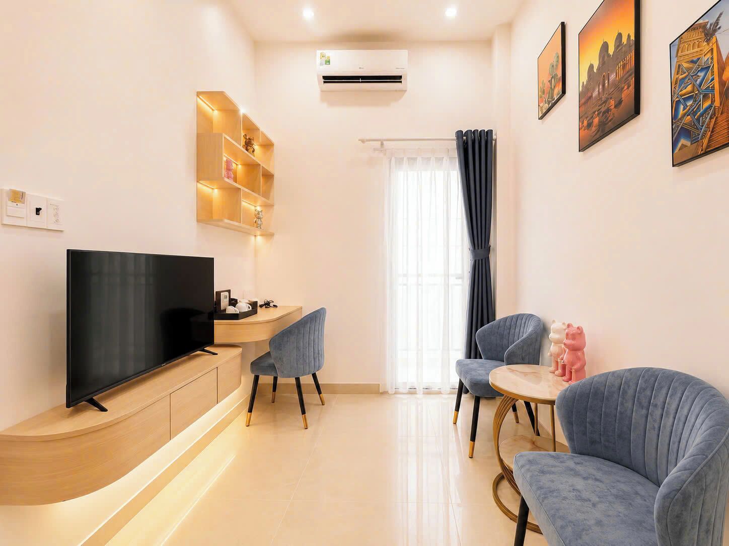A modern living room with a flat-screen TV, a wooden entertainment unit, a sofa, a chair, and a small round table.