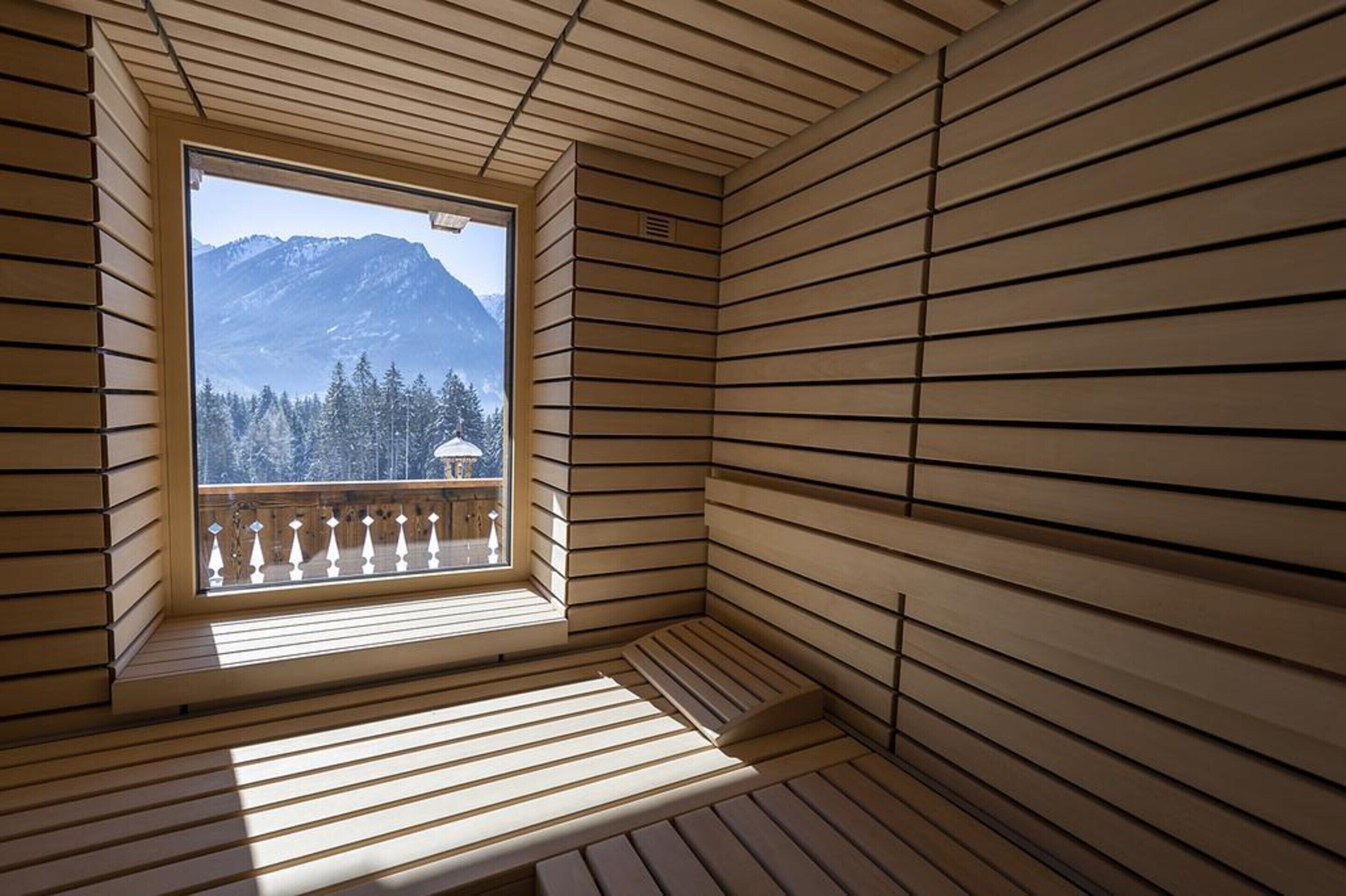 Une pièce en bois avec une fenêtre donnant sur une montagne et une forêt.