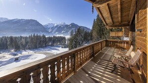 Eine Holzterrasse mit Blick auf schneebedeckte Berge und einen klaren Himmel.