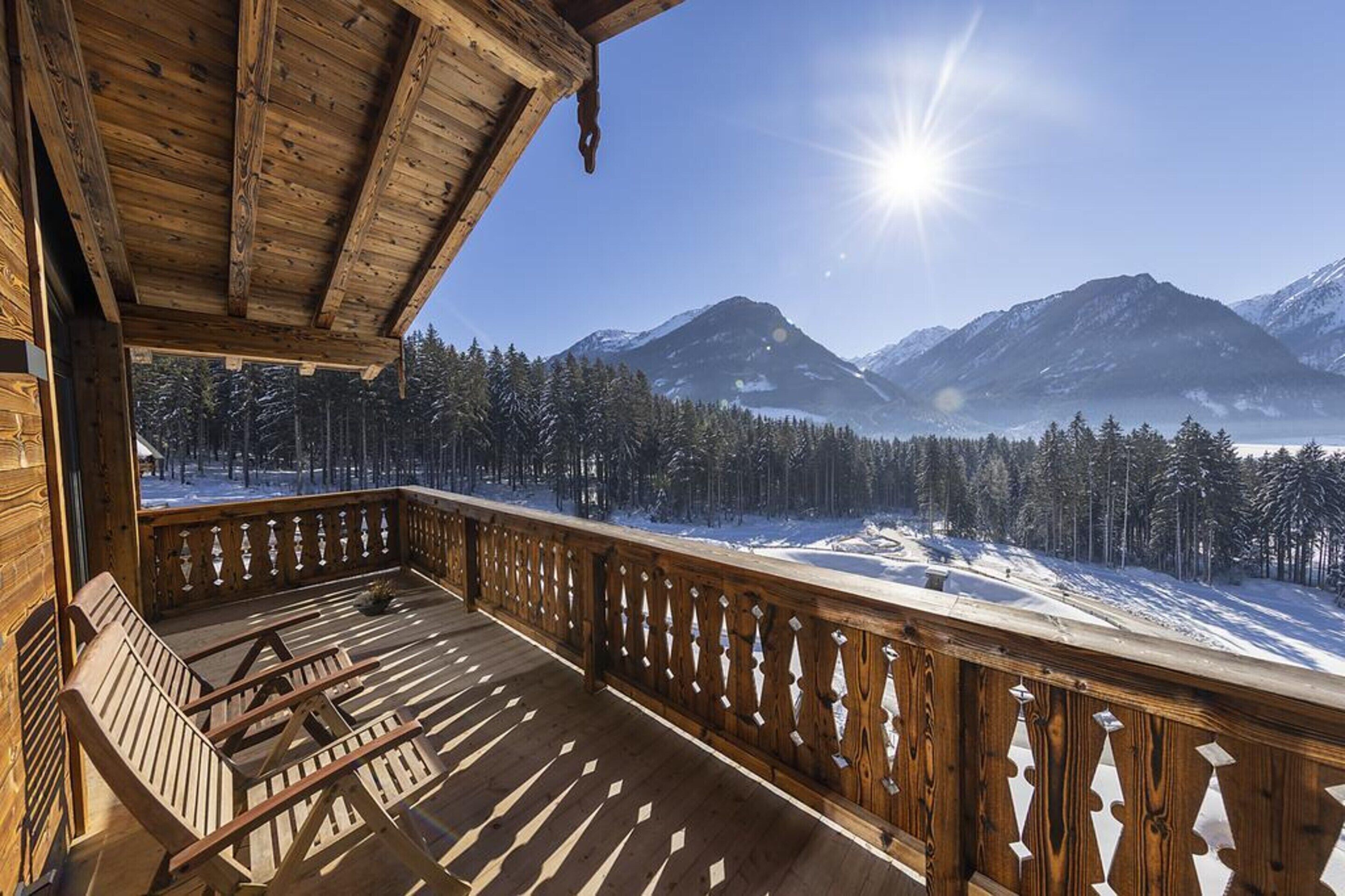 A wooden deck with a view of snow-covered mountains and a clear sky.