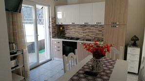 A modern kitchen with white cabinets, a tiled backsplash, and a dining table with chairs. - APARTMENT IN QUIET AREA, MINUTES FROM SPA PARKS AND BEACH, (FORIO)