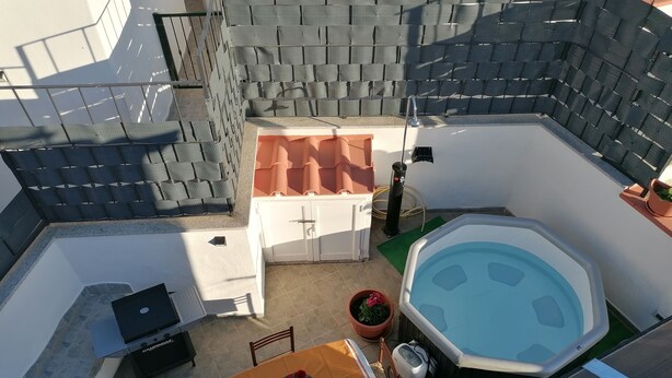 An outdoor patio with a hot tub, a barbecue grill, a table with a flower centerpiece, and a potted plant. - APARTMENT IN QUIET AREA, MINUTES FROM SPA PARKS AND BEACH, (FORIO)