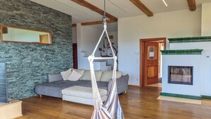 A spacious living room with a hanging chair, a grey sofa, a stone wall, and a fireplace.