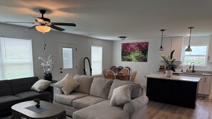 A modern living room with a grey sectional sofa, a coffee table, and a ceiling fan.