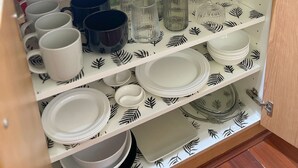 Ein Küchenschrank mit Regalen, auf denen verschiedene Gläser und Geschirr stehen.