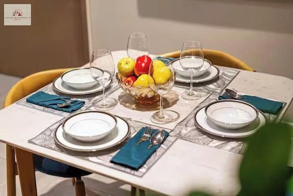 Una mesa de comedor dispuesta con platos, vasos y un frutero.