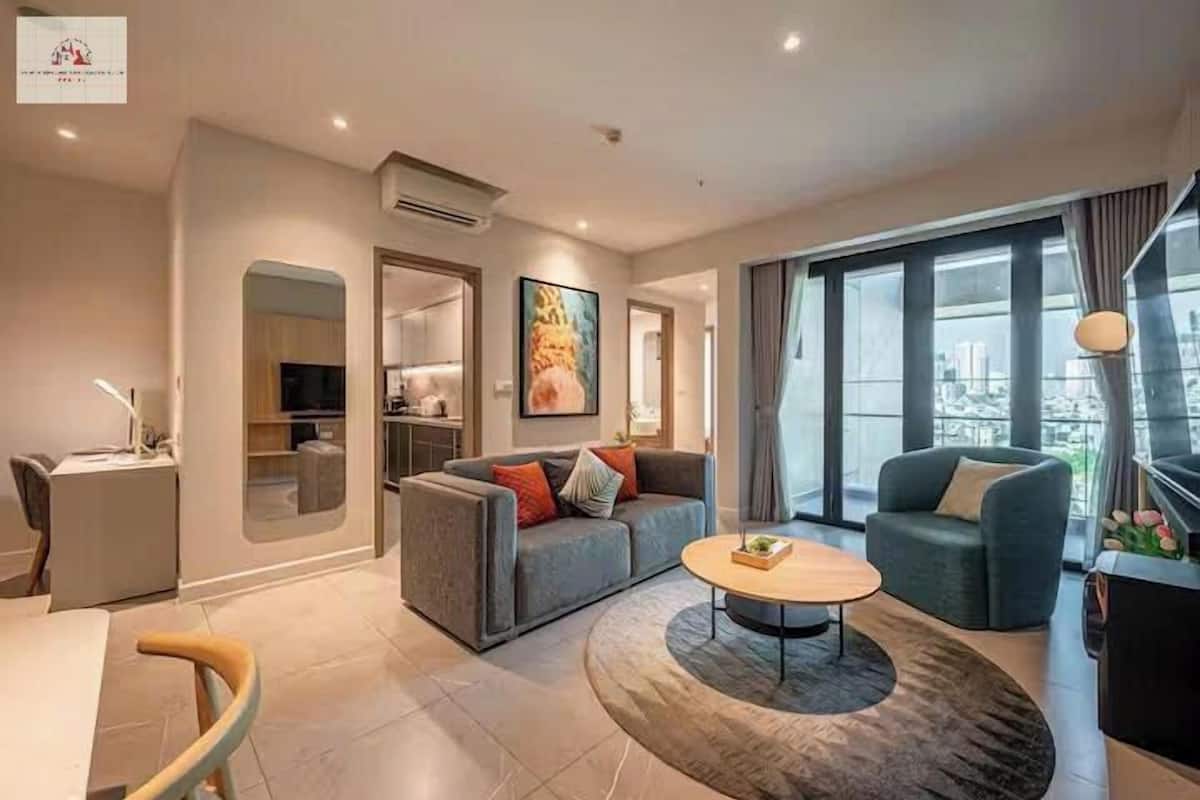 Una sala de estar moderna con un sofá, una mesita de centro y vistas de la ciudad a través de amplios ventanales.