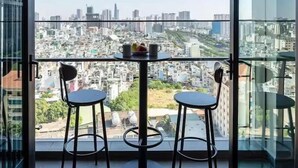 A modern room with a glass balcony overlooking a cityscape. - ZENITY Skyline Residences Suite (Ho Chi Minh City)