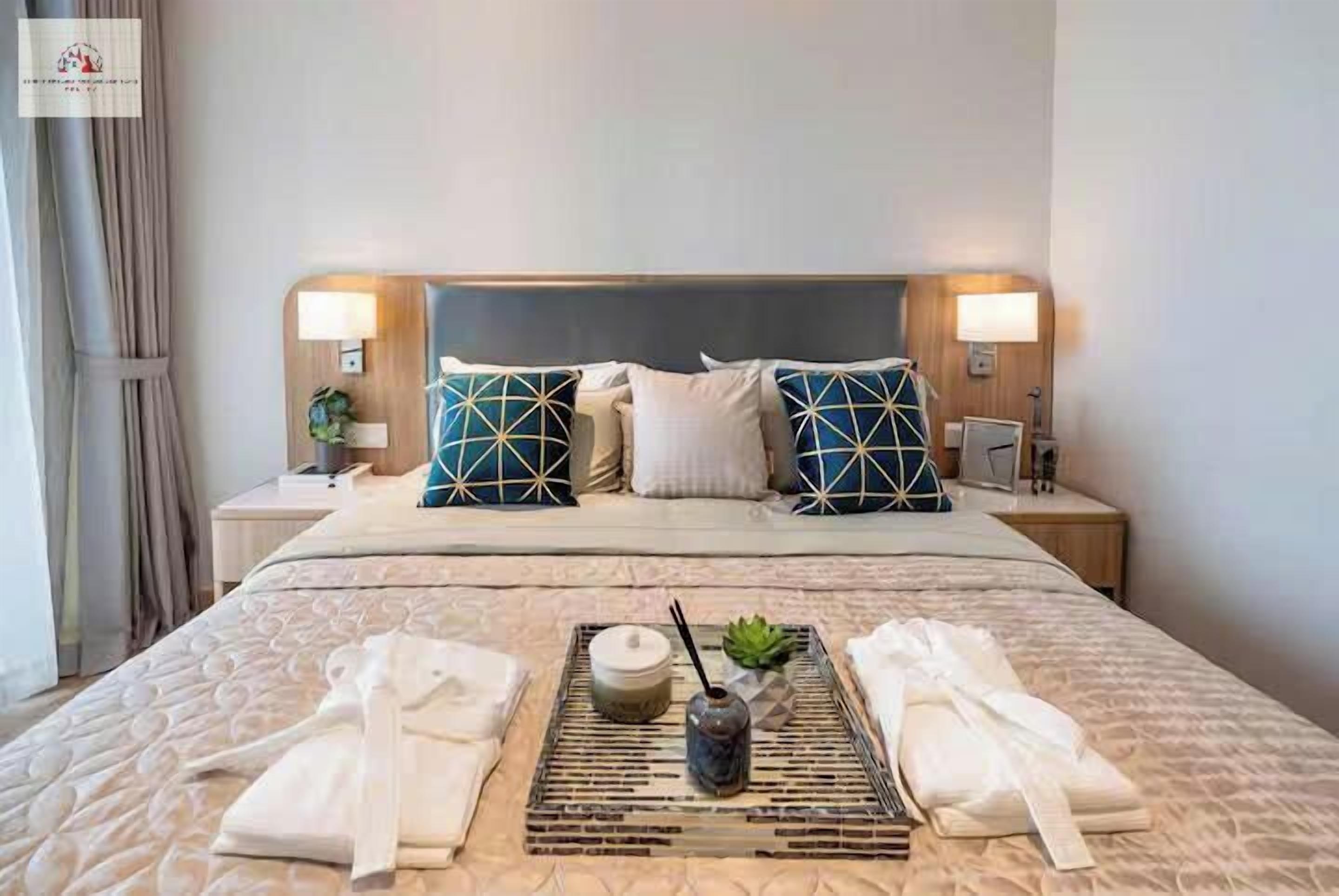 Quarto de hotel com uma cama grande, duas mesas de cabeceira, uma cabeceira e um porta-bandeja com toalhas e um vaso.