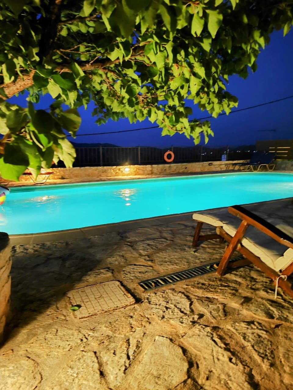 A swimming pool with a stone deck and lounge chairs.