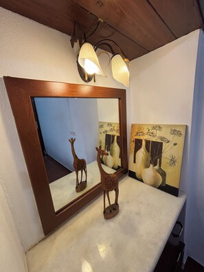 A mirror with a wooden frame, a giraffe figurine, and a vase with flowers. - Melina Stone Villa (Roumelí)