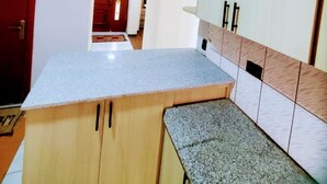 A kitchen with a granite countertop, wooden cabinets, and a red door.