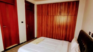 A bedroom with a large bed, wooden wardrobe, and a red door.