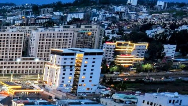 An urban area with a brightly lit basketball court surrounded by buildings.