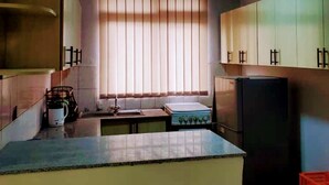A compact kitchen with a window, a refrigerator, and a sink.