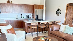 A modern living room with a kitchen area, featuring a sofa, coffee table, and a dining table with chairs. - Surf Paraiso @The Point (Los Cerritos, El Pescadero)