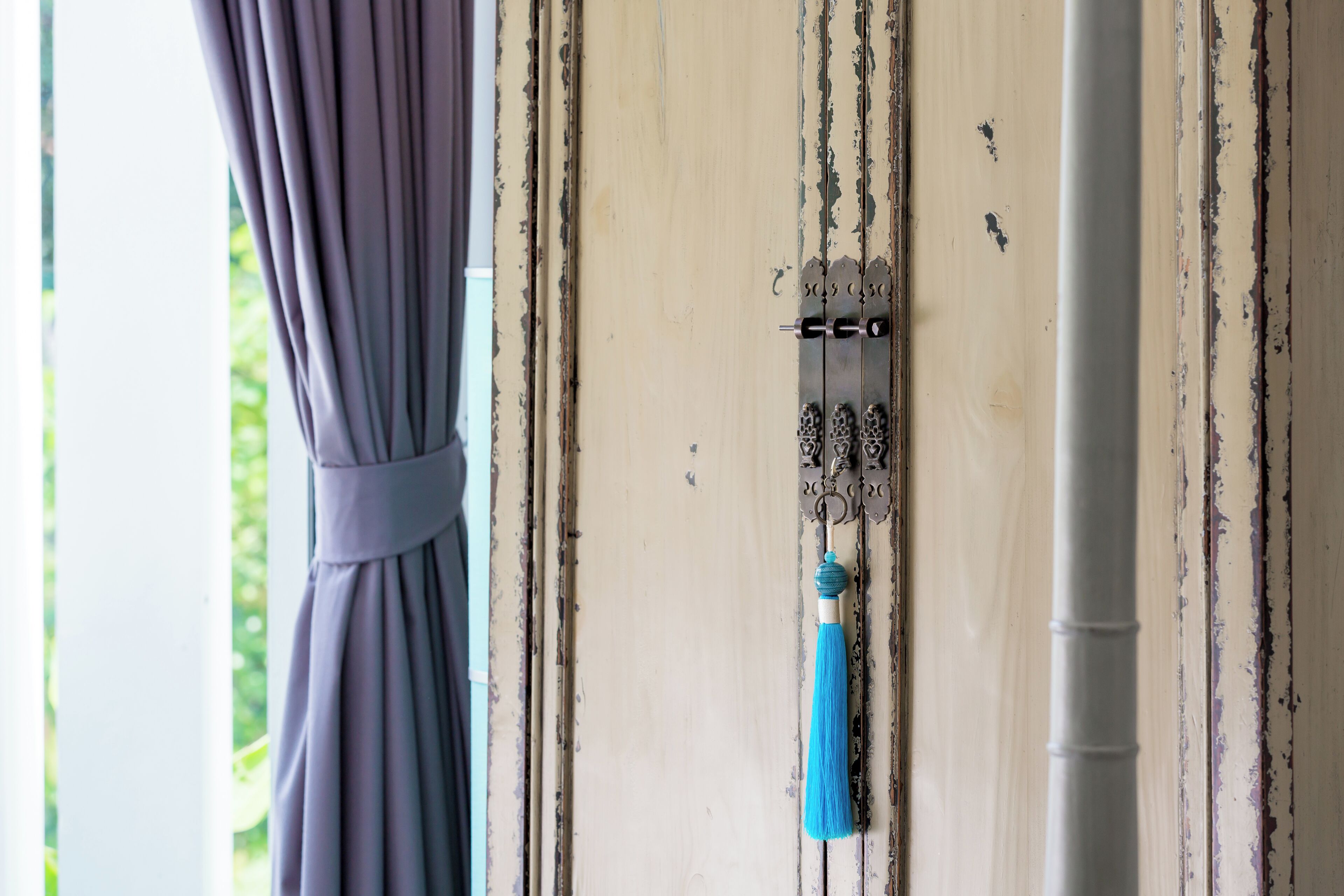 Une porte dotée d’un loquet métallique et d’une frange bleue qui y est suspendue.
