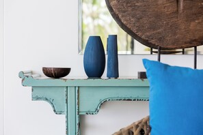 Ein mit Blau gestrichener Holztisch mit zwei blauen Vasen und einer dunklen Schüssel.