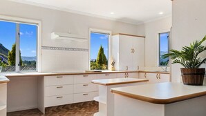 Een moderne keuken met witte kastjes, houten aanrecht en uitzicht op het omliggende landschap.