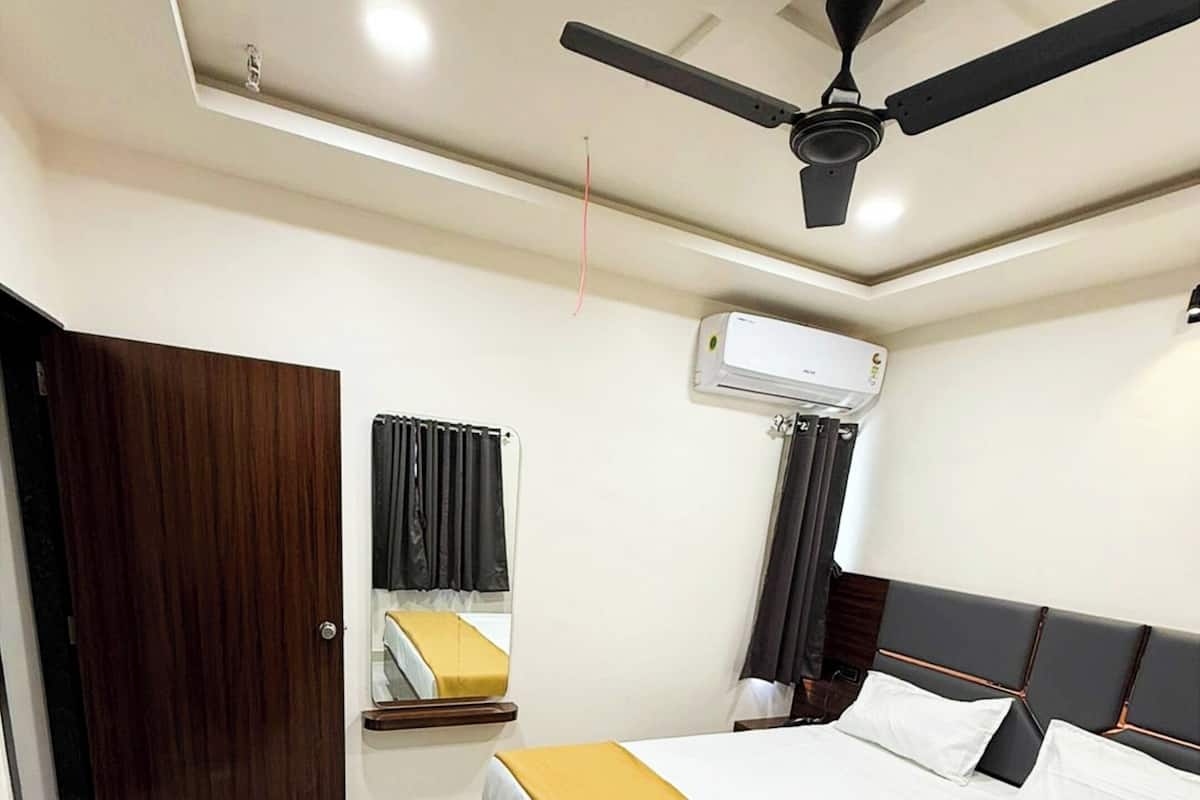 Ein Hotelzimmer mit einem Bett, einem Deckenventilator, einer Klimaanlage und einer Holztür.