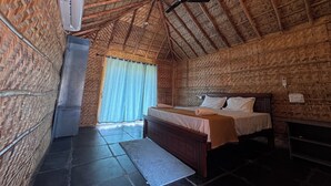 A room with a sloped ceiling, a bed with a wooden headboard, a ceiling fan, and a window with curtains.