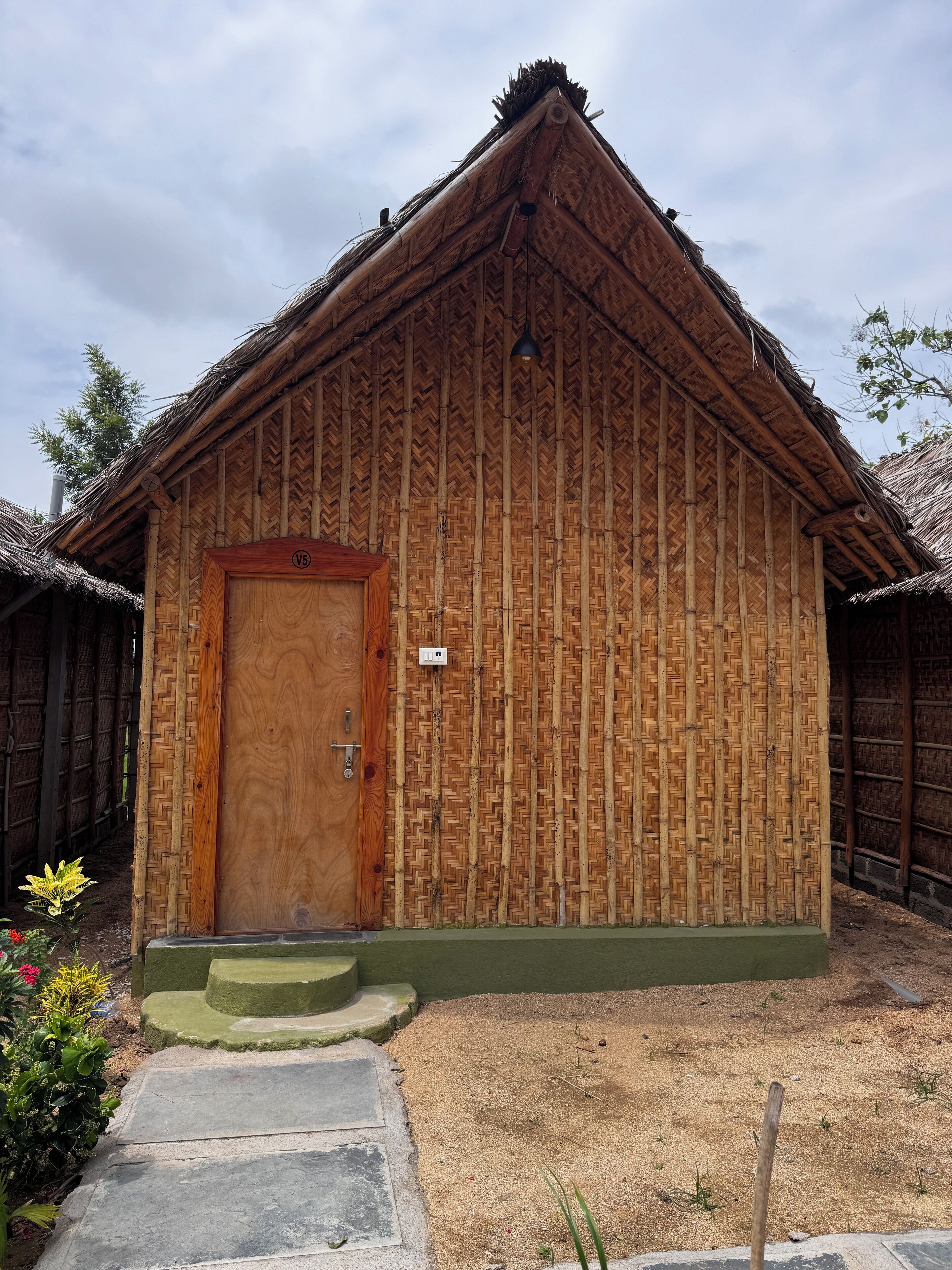 Ein traditionelles Holzhaus mit einem Reetdach, einer Holztür und einer kleinen Veranda.