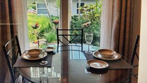 A dining table set for four with chairs, a glass of water, and plates.