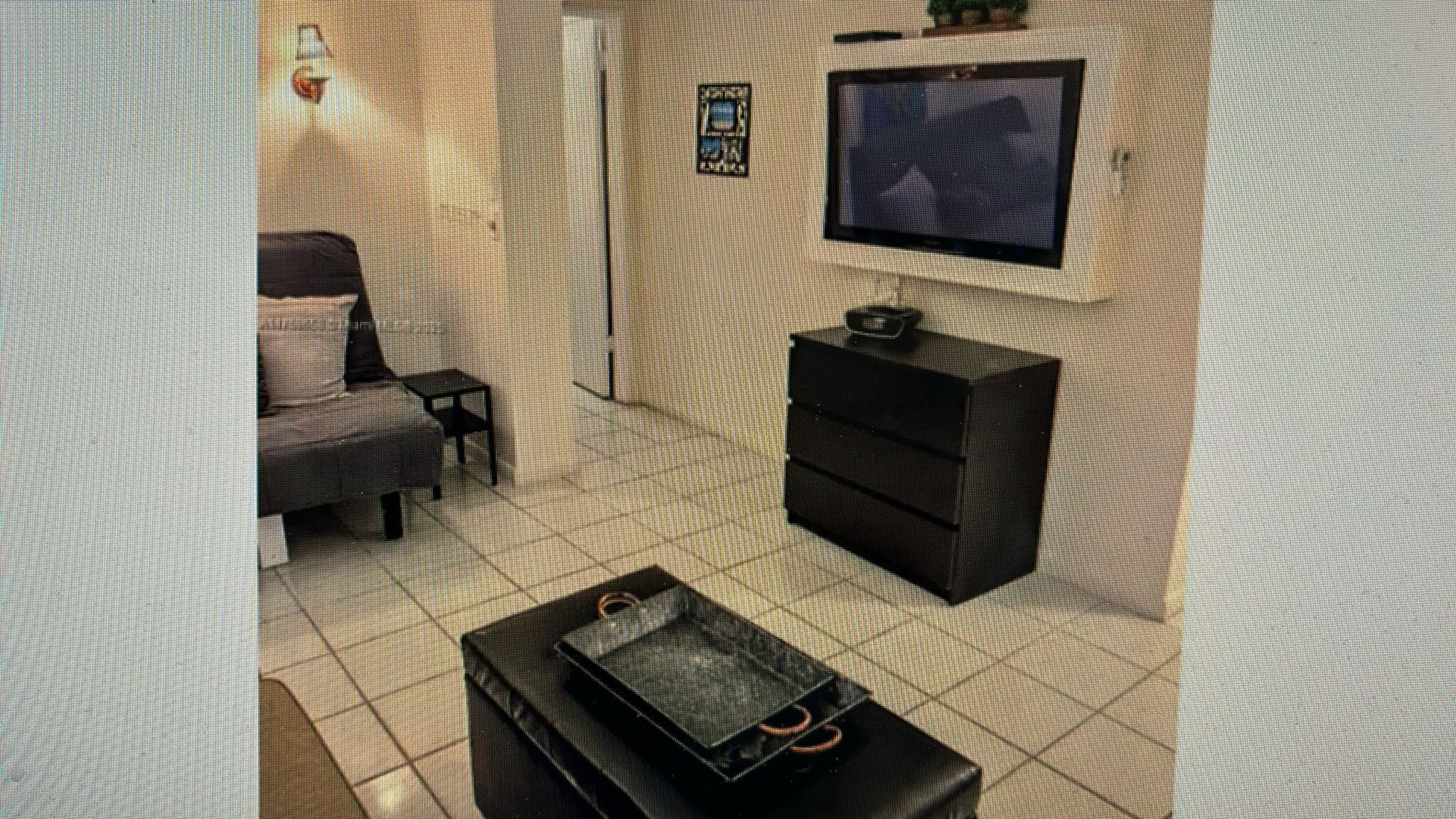 A room with a bed, a small table, a TV, and a cabinet.