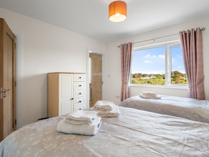Ein Hotelzimmer mit zwei Betten, einem Kleiderschrank und einem durchgehenden Türbogen sichtbaren Badezimmer.