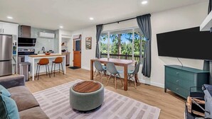 Una cocina moderna con comedor, televisor de pantalla plana y vistas al exterior.