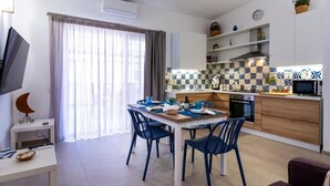 A modern living room with a dining table, chairs, a TV, and a sofa. - Vacation Home GIRO DI BITTA (Siculiana Marina)