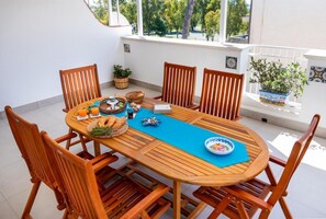 Une table de salle à manger en bois, avec six chaises, un set de table bleu et divers aliments.