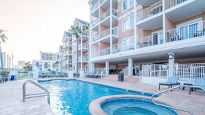 Un hôtel doté d’une piscine, de plusieurs balcons et d’un espace extérieur couvert avec des chaises longues.