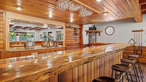 Interior de madera con una zona de bar, paredes de madera y un techo con lámparas colgantes.