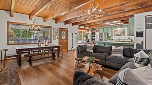 Un salón amplio con techo de madera, una gran mesa de comedor y una zona de estar acogedora.