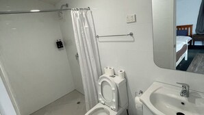 Een moderne badkamer met toilet, douche en wastafel.
