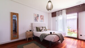 Une chambre à coucher avec un lit, une table de chevet, une lampe et une vue sur l’extérieur.