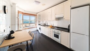 Une cuisine moderne avec des armoires blanches, un comptoir noir et une vue sur l’extérieur par une fenêtre.