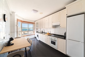 A modern kitchen with white cabinets, a black countertop, and a view of the outdoors through a window.