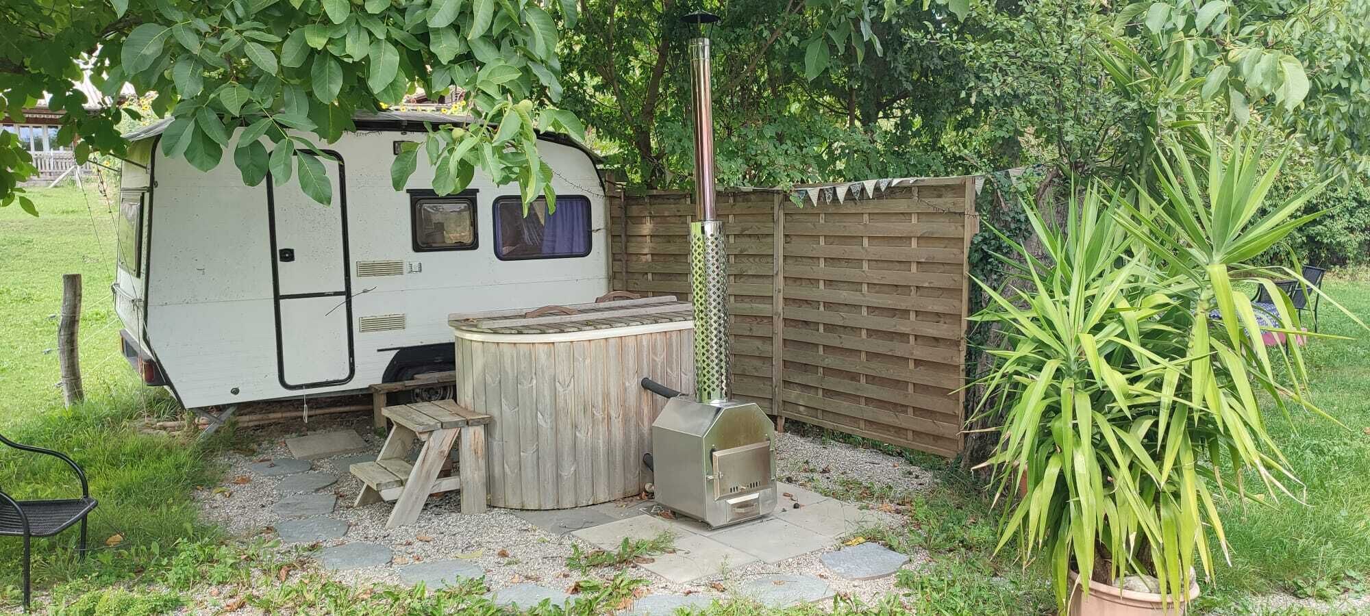 A recreational vehicle with a wooden table and a barbecue grill in a backyard.