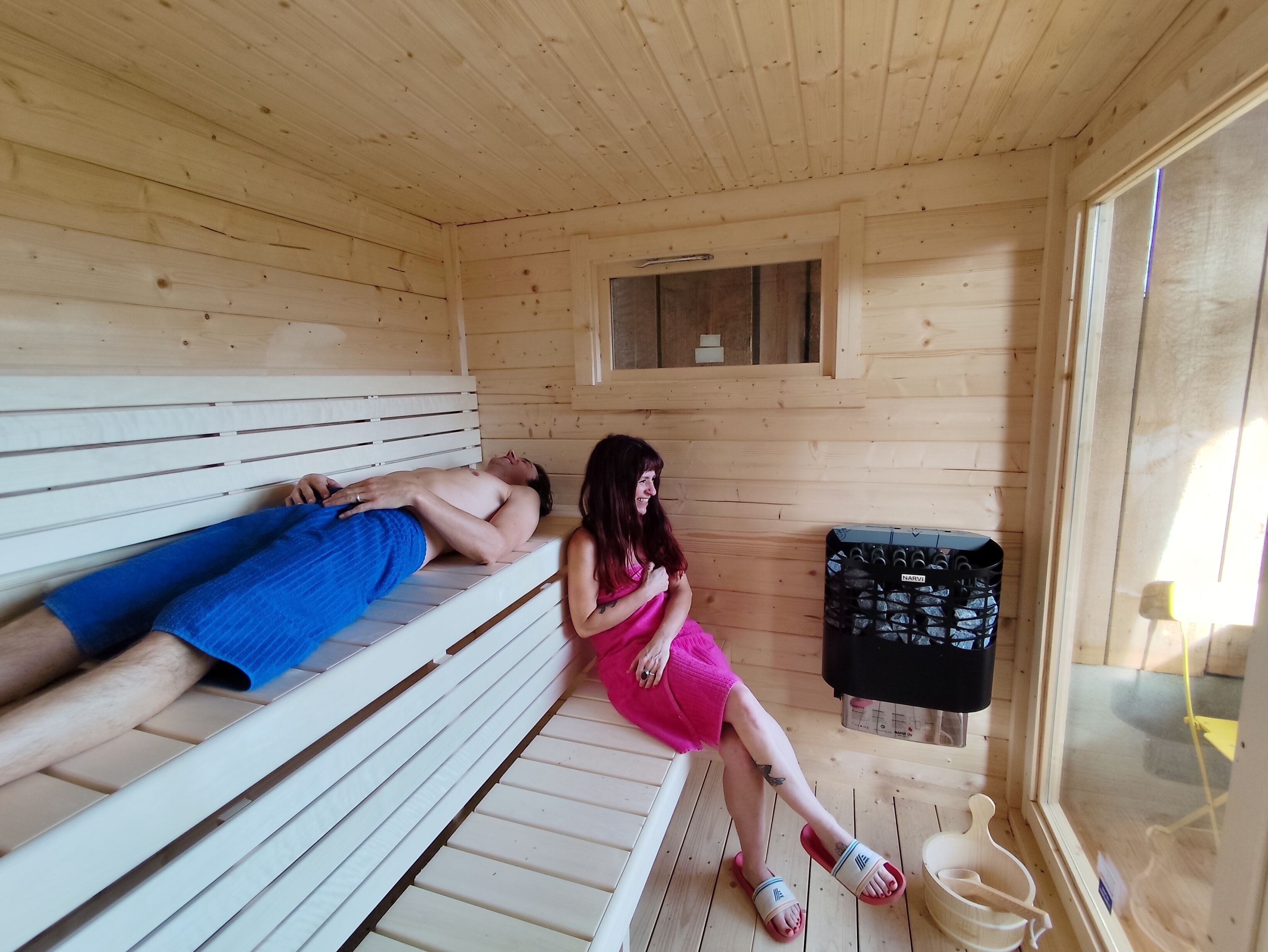 Una sauna de madera con bancos, una ventana pequeña y un panel de control.