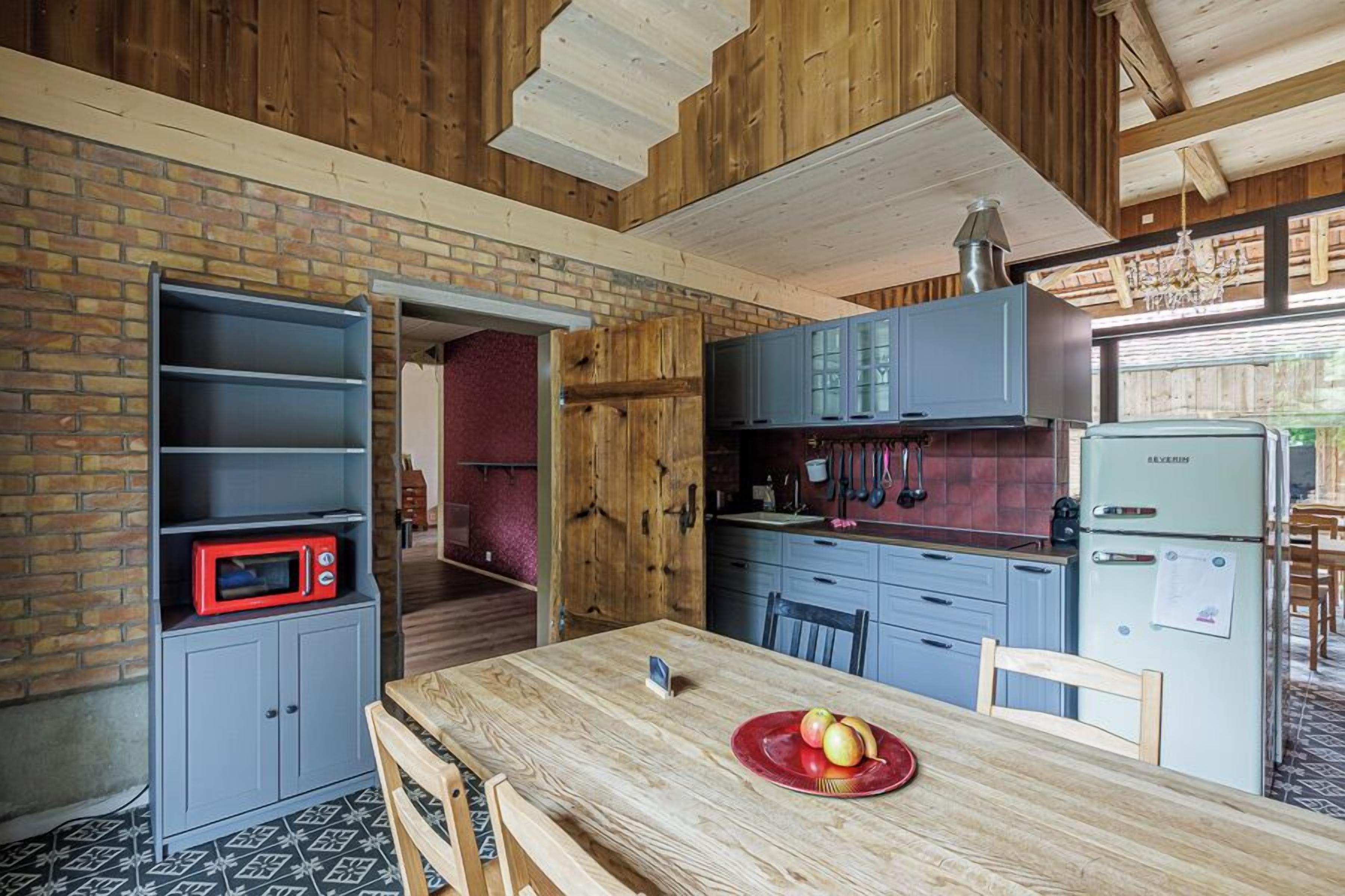 A kitchen with wooden walls, a brick backsplash, and a vintage-style refrigerator.