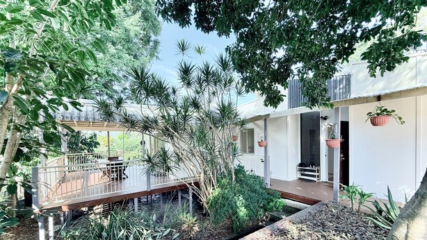 Una casa con un espacio exterior techado, un patio y un jardín con diversas plantas.